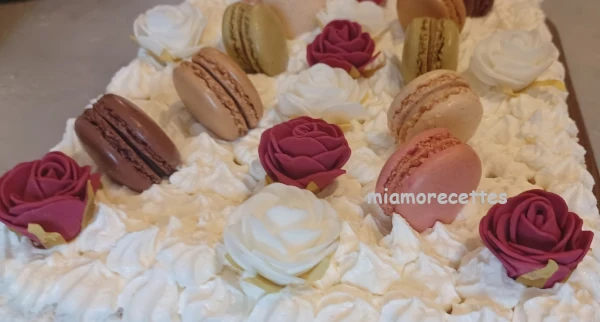 Gâteau à la crème décoré avec des macarons et des fleurs rouges et blanches