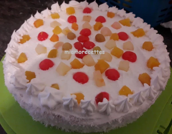 Gâteau à la crème décoré avec des morceaux de fruits et de la noix de coco